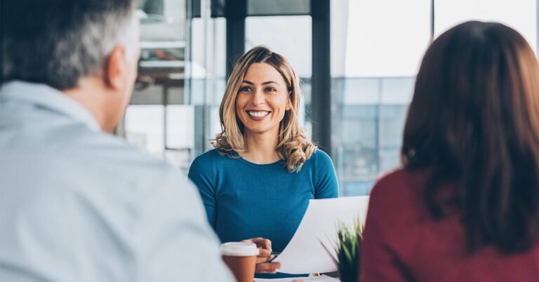 professional woman at desk with clients GettyImages 1078228880 1200w 628h